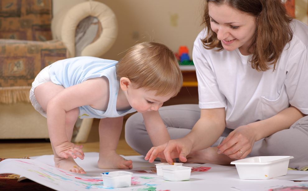 Kvinde og lille barn maler med fingermaling